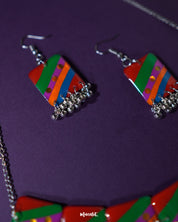Side-angle shot of the Gulrang multicolor resin earrings, showcasing bold red, green, blue, and purple striped rectangular charms with dotted accents and delicate silver bead tassels, highlighting their vibrant colors and intricate craftsmanship – Muselot.