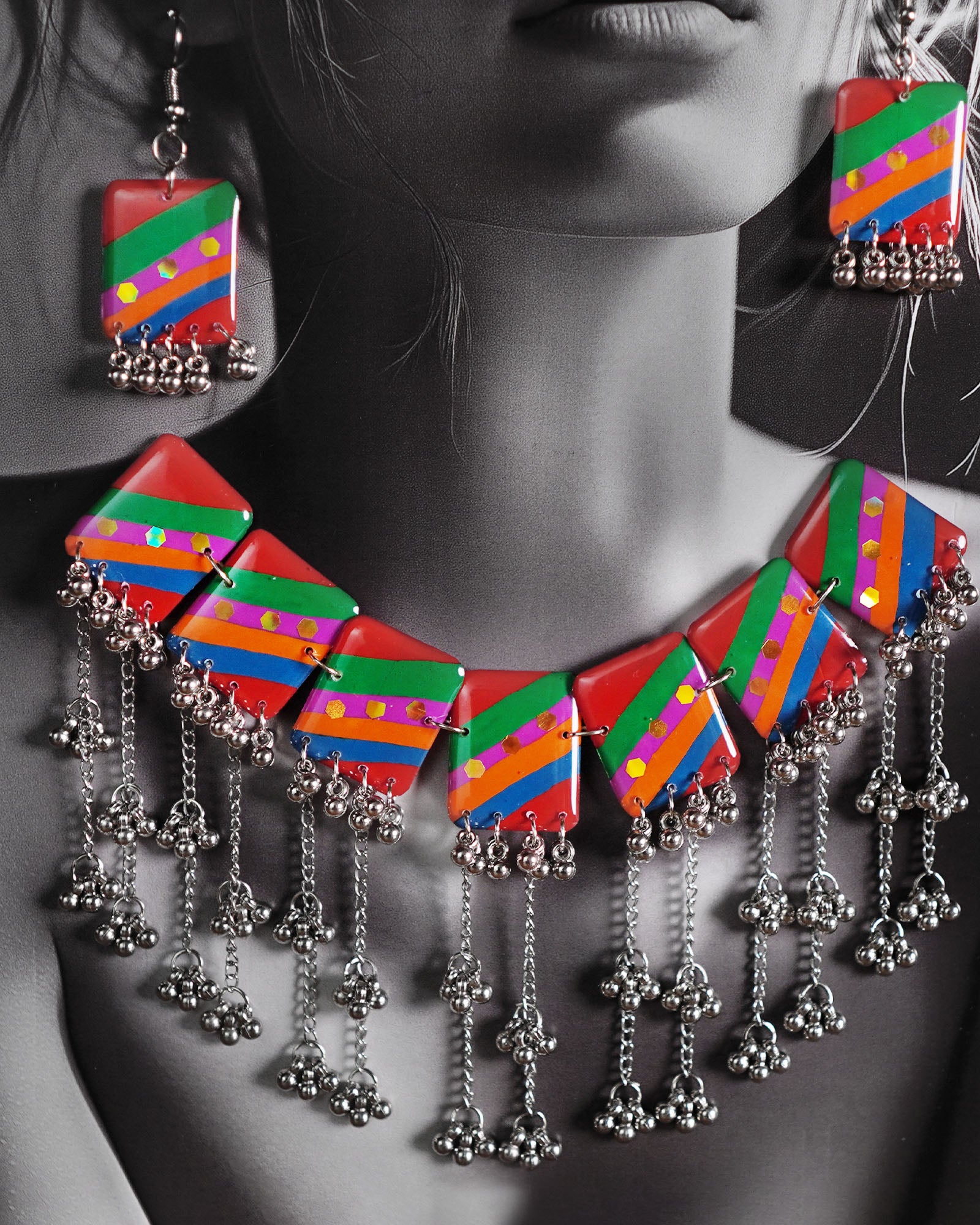 Close-up of model wearing the Gulrang multicolor resin jewelry set, highlighting the bold red, green, blue, and purple striped rectangular charms with dotted accents and cascading silver bead tassels on the necklace, paired with matching earrings, capturing the vibrant details and craftsmanship – Muselot.