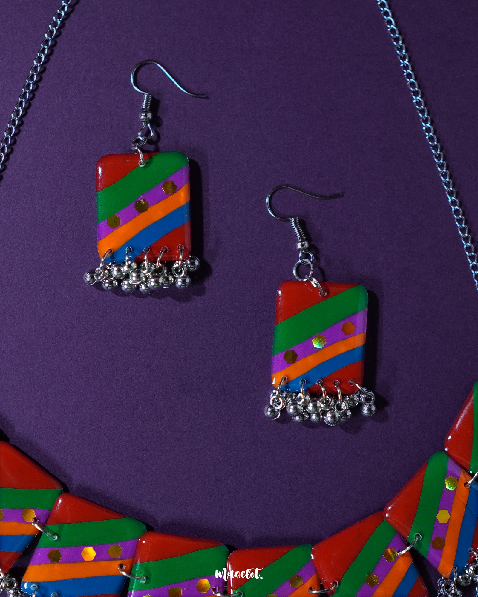 Top-angle shot of the Gulrang multicolor resin earrings, featuring bold red, green, blue, and purple striped rectangular charms with dotted accents and delicate silver bead tassels, capturing their vibrant design and fine detailing – Muselot.