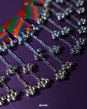 Zoomed-in view of the Gulrang multicolor resin jewelry set’s ghungroo accents, featuring intricate silver bead tassels hanging from bold red, green, blue, and purple striped rectangular charms, showcasing fine craftsmanship and vibrant detailing – Muselot.