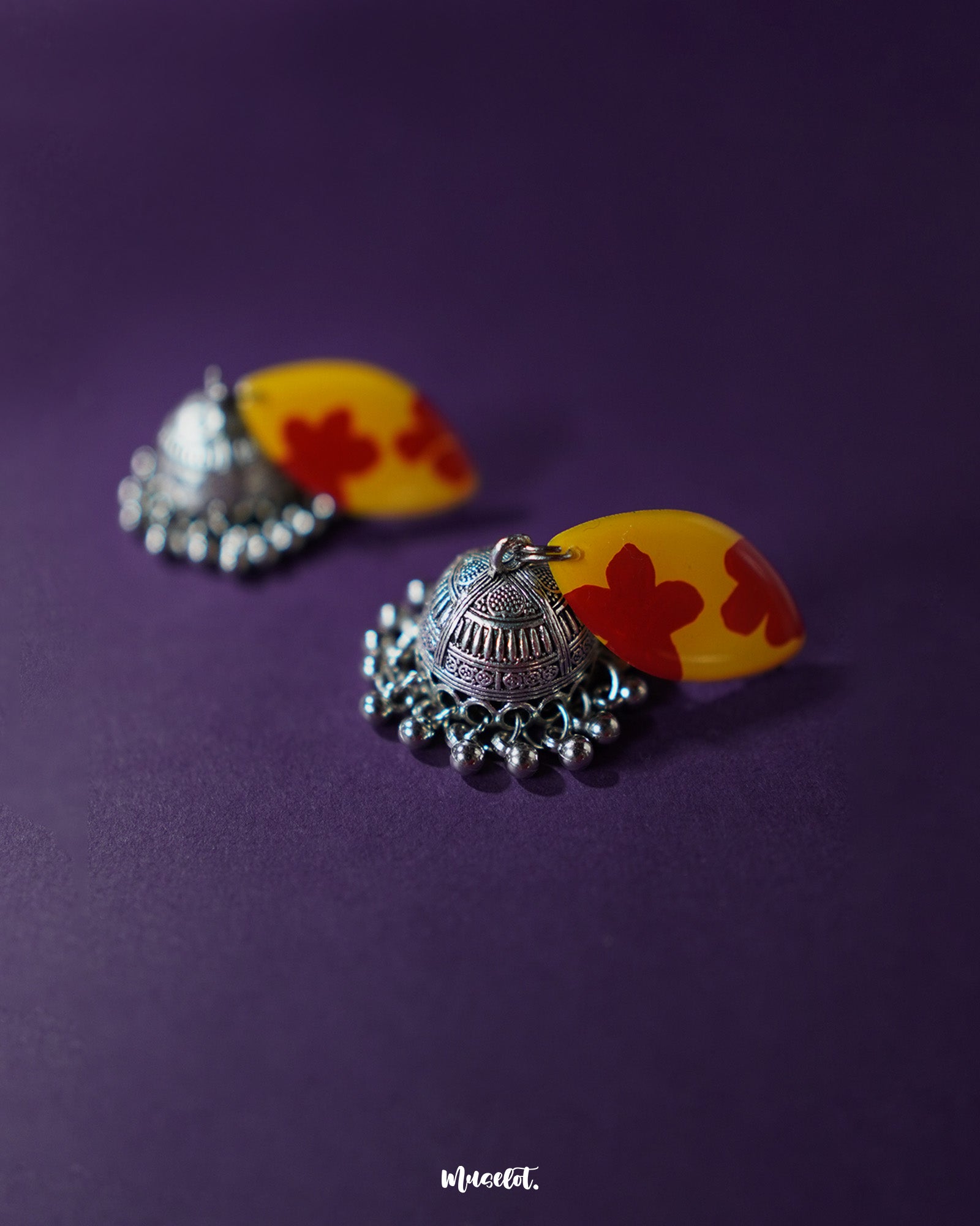 Close-up of Gulrukh floral jhumkas, focusing on the vibrant yellow-red motif and textured oxidized silver dome against a clean backdrop – Muselot.
