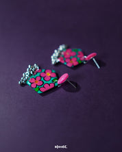 Gulshafa pink floral drop earrings, set against a dark purple background, with soft pink hues and intricate floral patterns that bring out their elegant yet playful boho flair — Muselot.