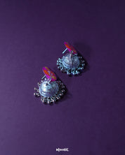 Gulzarish floral jhumkas with marquise-shaped tops painted in rich purple and adorned with orange and yellow leaf motifs accented by green dots, paired with ornate oxidized silver dome-shaped drops and delicate hanging beads, elegantly displayed to showcase their intricate craftsmanship – Muselot.