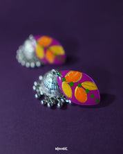 Zoomed-in view of the upper part of the Gulzarish floral jhumkas, showcasing the marquise-shaped tops painted in vibrant purple with orange and yellow leaf motifs accented by green dots, highlighting the intricate hand-painted detailing – Muselot.