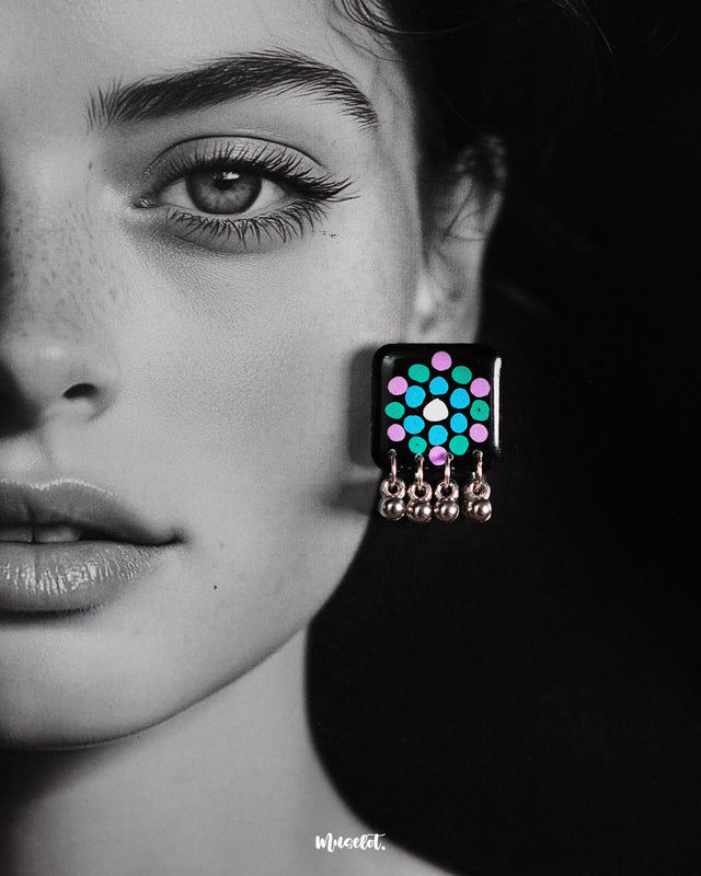 Model wearing handmade black earrings with teal and purple polka design and silver ghungroo drops, highlighting their bold ethnic appeal – Muselot.