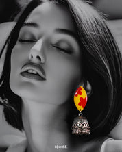 Model wearing handmade floral jhumkas, showcasing the vibrant yellow and red top with oxidized silver jhumka drops, styled to highlight their artisanal, traditional appeal – Muselot.