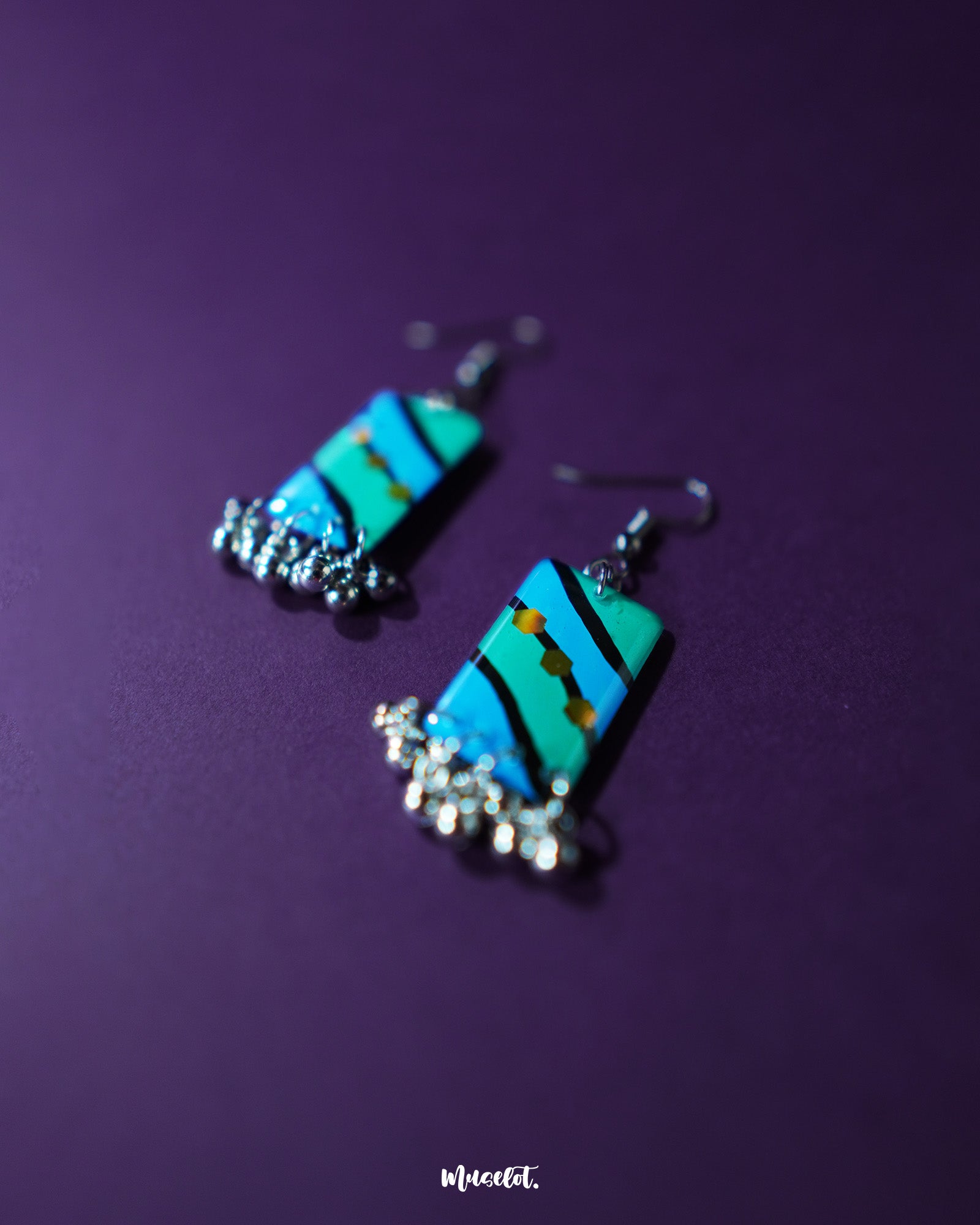 A close-up of the Jaltarang handmade strip hook earrings reveals intricate metallic detailing and smooth texture, highlighting their handcrafted charm and fluid drop silhouette — Muselot.