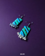 A close-up of the Jaltarang handmade strip hook earrings reveals intricate metallic detailing and smooth texture, highlighting their handcrafted charm and fluid drop silhouette — Muselot.