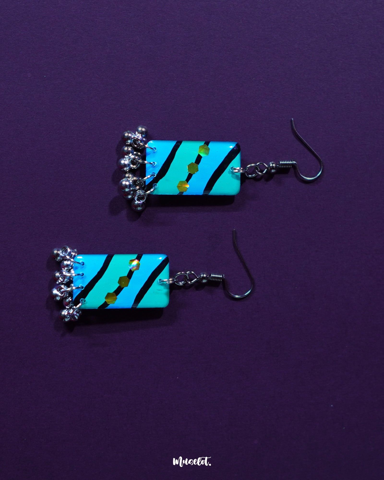 The Jaltarang handmade strip hook earrings rest on a soft fabric backdrop, showcasing their lightweight build and artistic, handcrafted form that blends tradition with contemporary elegance — Muselot.