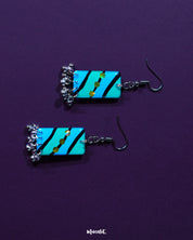 The Jaltarang handmade strip hook earrings rest on a soft fabric backdrop, showcasing their lightweight build and artistic, handcrafted form that blends tradition with contemporary elegance — Muselot.