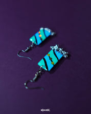 Jaltarang handmade strip hook earrings placed on a textured neutral surface, highlighting the gentle curves and balanced design of the vertical strips with an artisanal charm — Muselot.