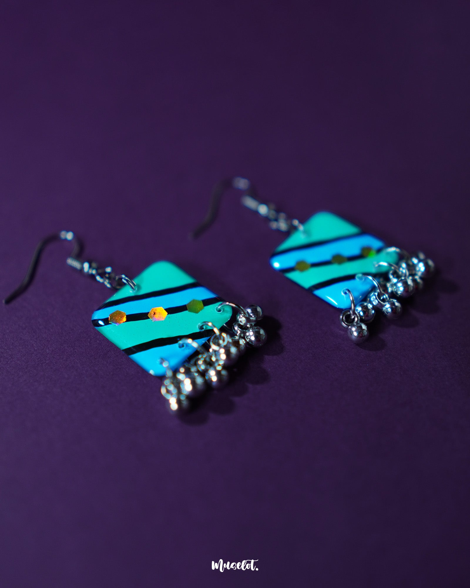 Jaltarang square strip earrings, highlighting the structured square studs and fluid metallic drops that dangle gracefully, adding a touch of bold elegance to her look — Muselot.