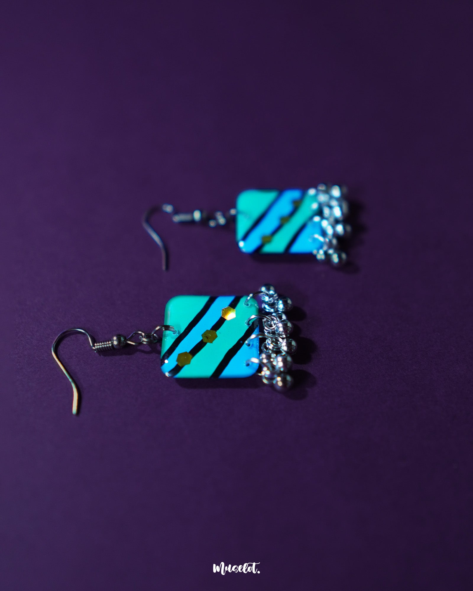 The Jaltarang square strip earrings rest against a neutral backdrop, showcasing their geometric square tops and sleek hanging strips that blend modern minimalism with a hint of statement flair — Muselot.