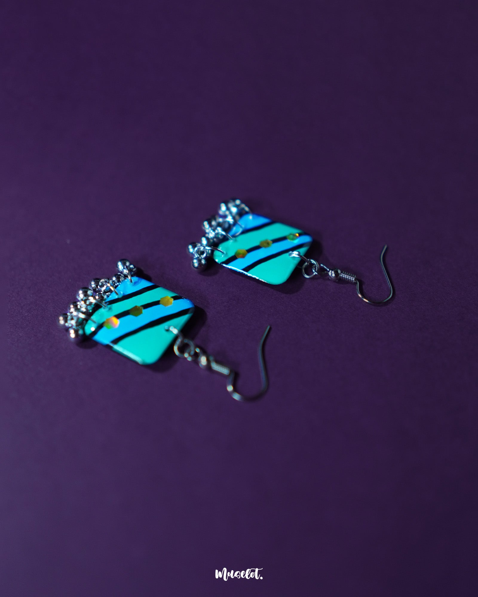 A pair of Jaltarang square strip earrings displayed on a textured white backdrop, highlighting the sharp geometry of the square top and the rhythmic flow of the dangling silver strips — Muselot.