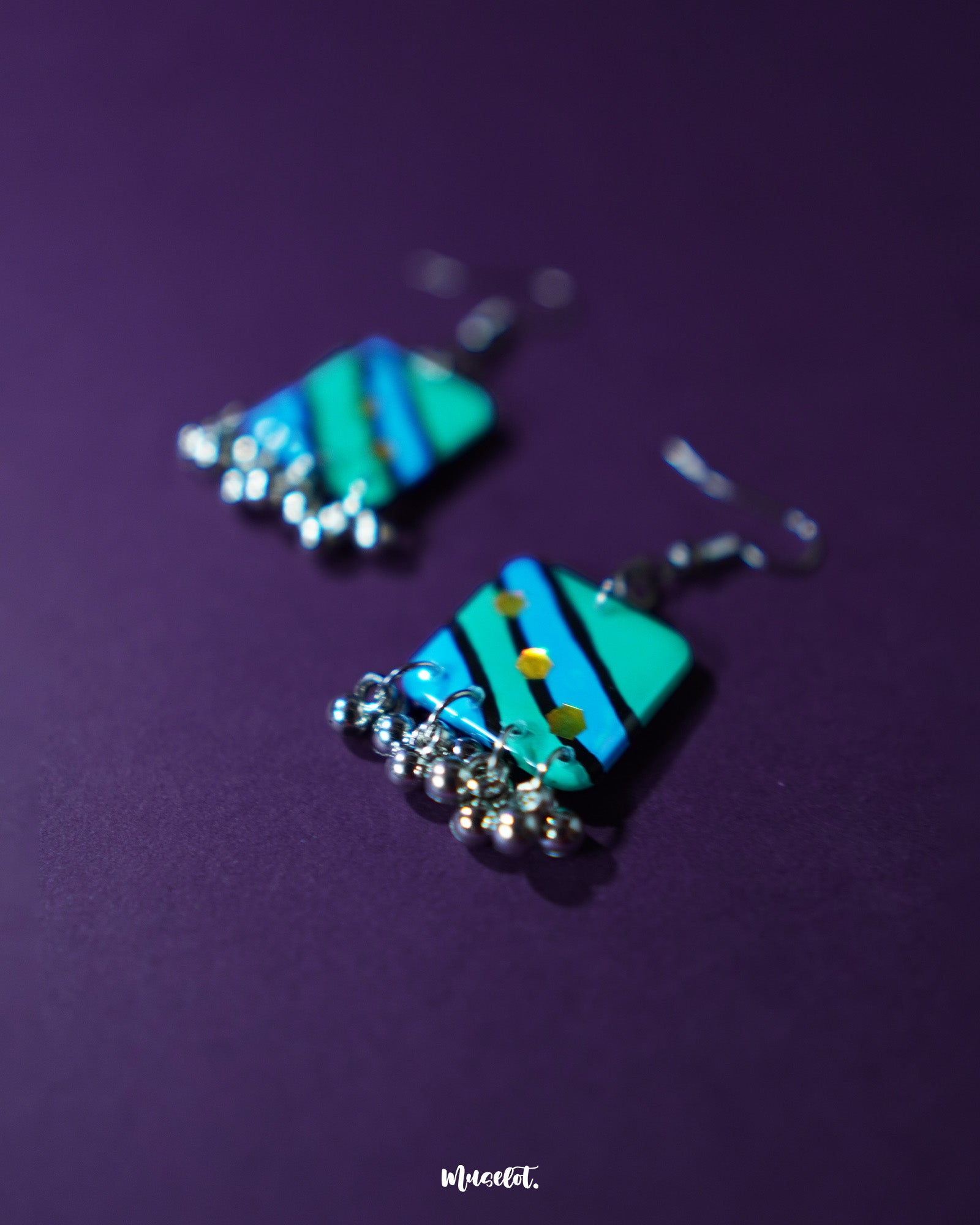 Close-up of Jaltarang square strip earrings placed on a rustic surface, showcasing the fine texture of the square studs and the neat alignment of the metallic hanging strips that lend a contemporary statement — Muselot.