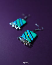 Close-up of Jaltarang square strip earrings placed on a rustic surface, showcasing the fine texture of the square studs and the neat alignment of the metallic hanging strips that lend a contemporary statement — Muselot.
