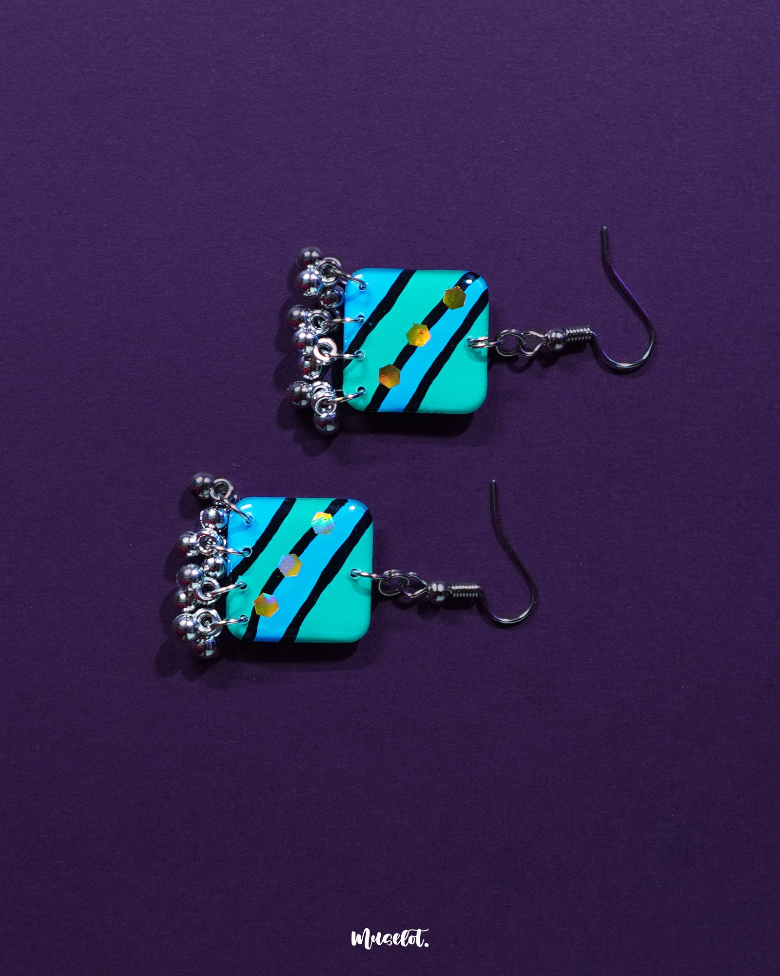 Jaltarang square strip earrings resting elegantly on a soft ivory surface, capturing the interplay of structured squares and fluid metallic strands for a modern boho charm — Muselot.