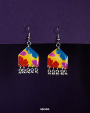 Jharokhe multicolor floral earrings displayed on a deep purple background, featuring vibrant petal patterns in red, blue, pink, and yellow with playful silver ghungroo detailing for a bold, joyful finish — Muselot.