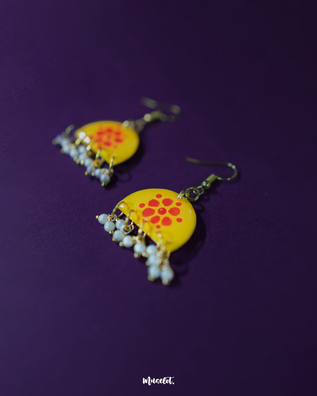 Kesarika floral yellow hook earrings, highlighted against a rich purple background, with vivid red blooms and delicate craftsmanship that lend a cheerful yet elegant flair to the design — Muselot.