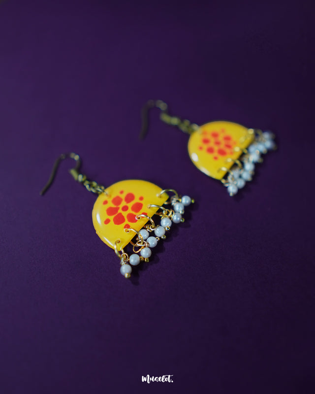 Kesarika floral yellow hook earrings, set against a rich purple background, adorned with striking red floral accents and intricate handcrafted details that add a bold, elegant flair to the design — Muselot.
