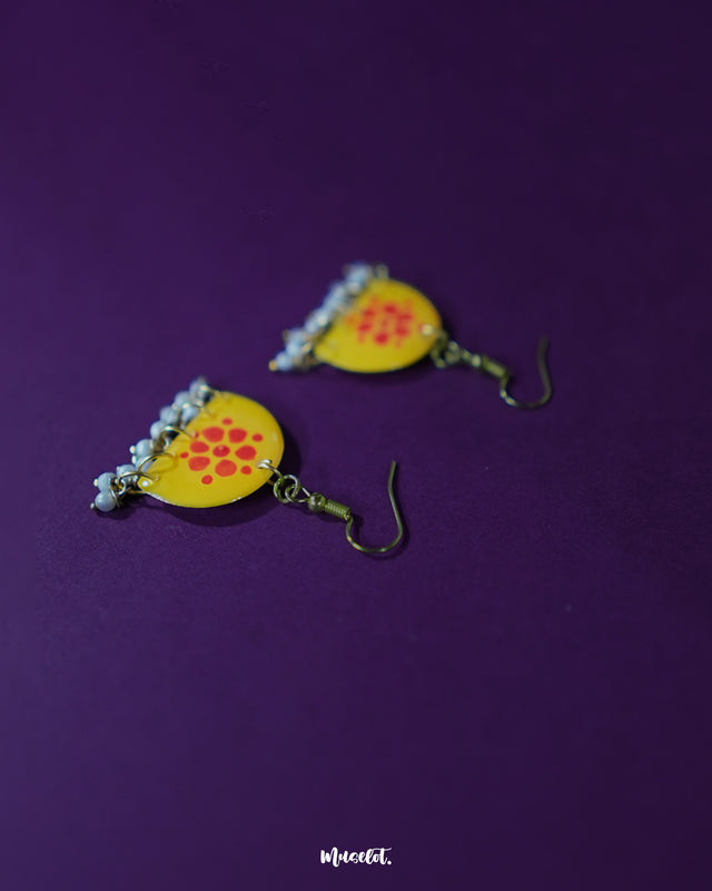 Kesarika floral yellow hook earrings, displayed against a deep purple background, featuring vibrant red floral motifs and delicate craftsmanship that bring a lively, bold touch to the overall elegance — Muselot.