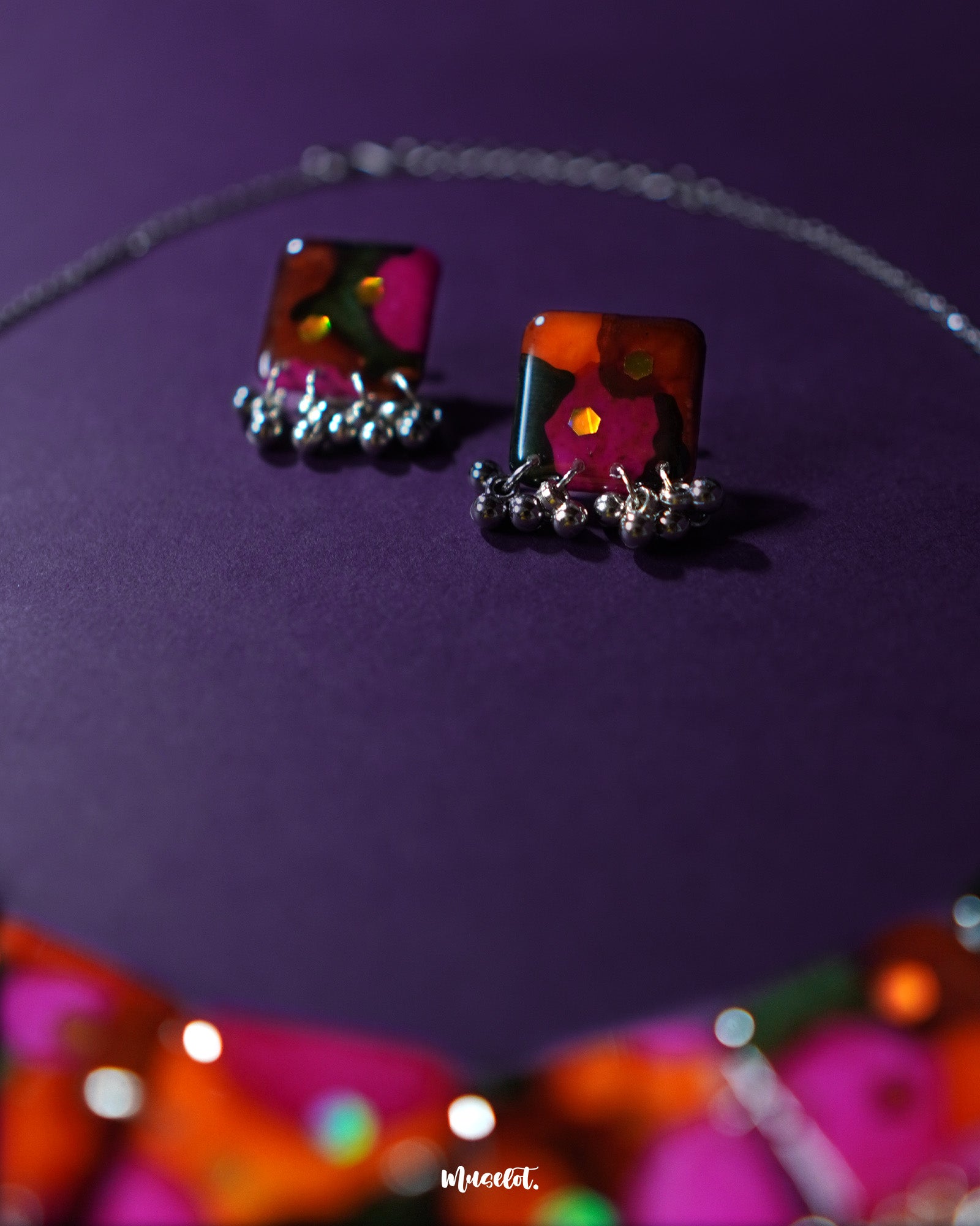 Khushk Gul handmade floral earring featuring a square charm with vibrant pink, orange, and green abstract floral patterns accented by delicate silver beads, beautifully showcased to highlight its intricate design and lively colors – Muselot.