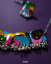 A close-up of the Kohsar colorful jewelry set highlighting the intricate detailing of its multicolor beads and antique-finish metal accents, laid on a deep purple background to enhance its vibrant boho charm — Muselot