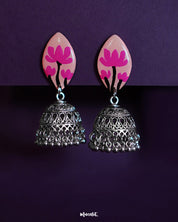 Kumudini jhumkas  handcrafted earrings featuring lotus-pink painted studs and oxidized silver dome-shaped jhumkas with intricate filigree and dangling ghungroos, displayed on a deep purple background-Muselot