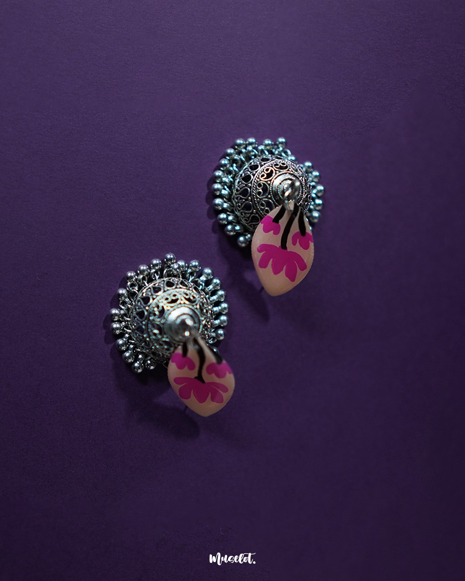 Front display of Kumudini pink lotus jhumkas, showcasing the floral dome and subtle hand-painted details against a simple background – Muselot.
