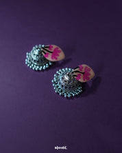 Pink lotus-inspired Kumudini handcrafted jhumkas displayed against a purple background, highlighting their delicate floral design and traditional elegance – Muselot.