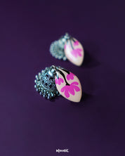 Close-up of Kumudini pink lotus jhumkas, showcasing intricate hand-painted petals and traditional craftsmanship with a soft backdrop – Muselot.