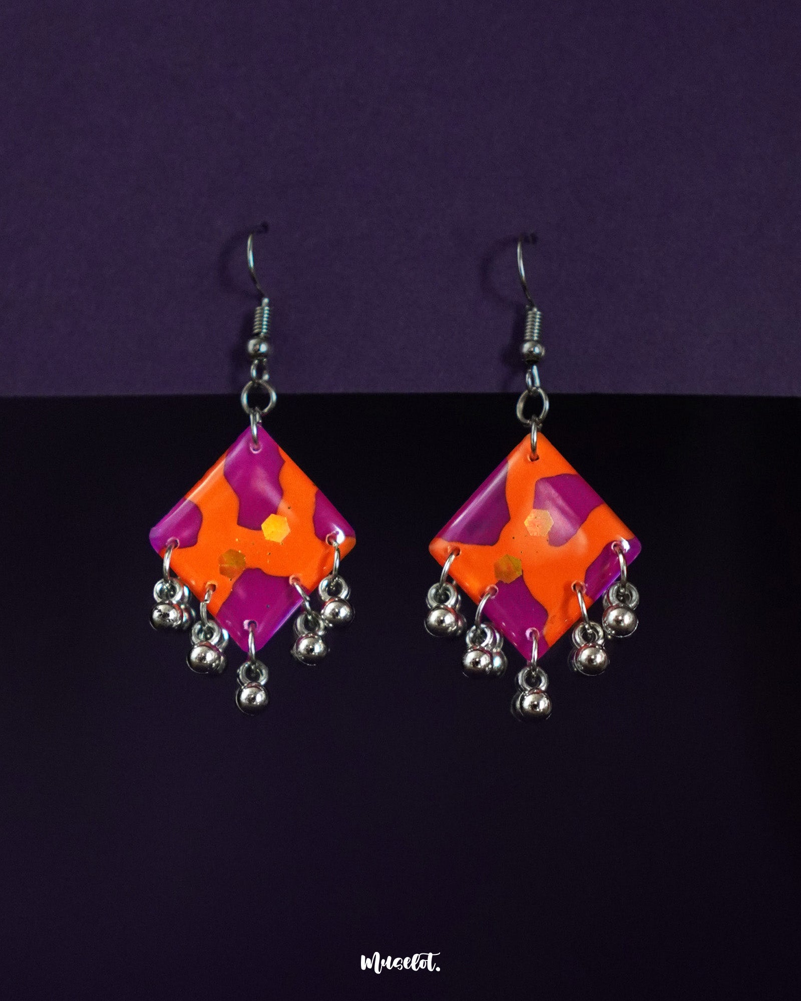 The laalsavera abstract hook earrings are placed against a deep purple background, showcasing their bold artistic silhouette, creating a striking blend of contemporary style and ethnic flair– Muselot