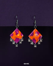 The laalsavera abstract hook earrings are placed against a deep purple background, showcasing their bold artistic silhouette, creating a striking blend of contemporary style and ethnic flair– Muselot