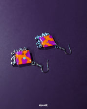 The Laalsavera earrings bring together bold design and graceful craftsmanship, with their elegance enhanced by the rich purple background — Muselot.