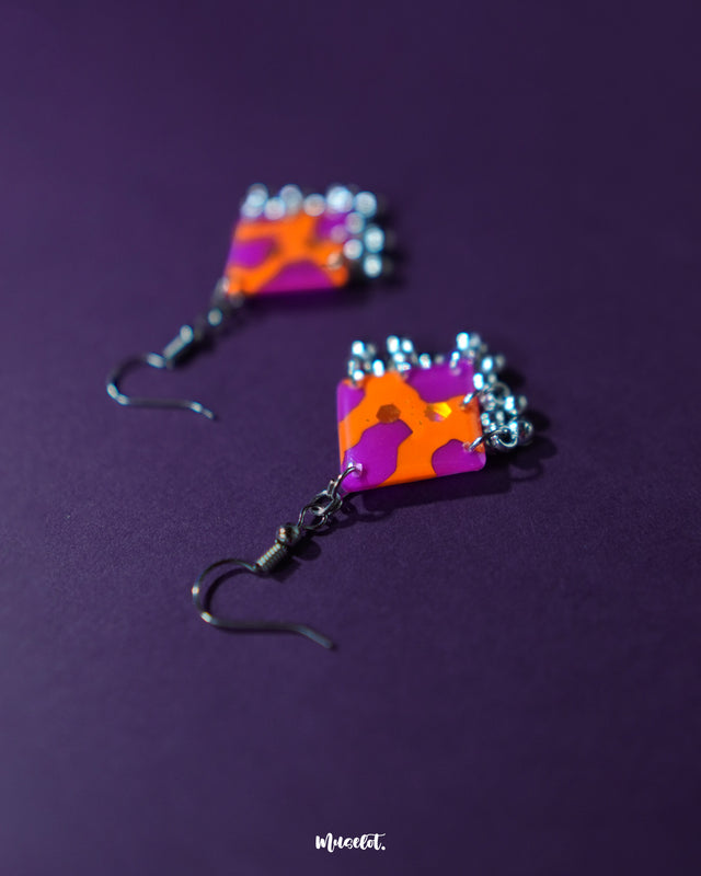 The Laalsavera hook earrings, elegantly designed and set against a bold purple background, showcase timeless beauty — Muselot.