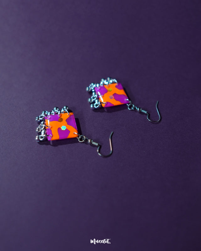 The Laalsavera hook earrings exude charm with their artistic curves, subtly highlighted against a bold purple background — Muselot.