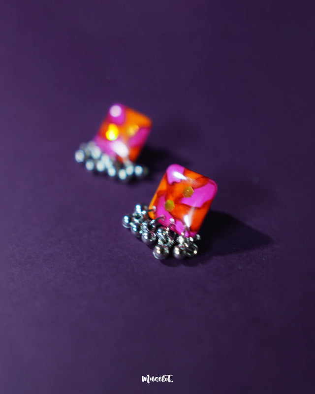 The Laalsavera stud earrings, featuring a chic design, beautifully pop against a rich purple background — Muselot.