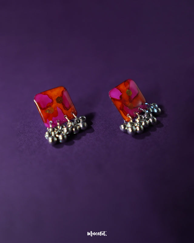 The Laalsavera stud earrings offer a sleek, minimalist design, adding a touch of sophistication, perfectly complemented by a purple background — Muselot.
