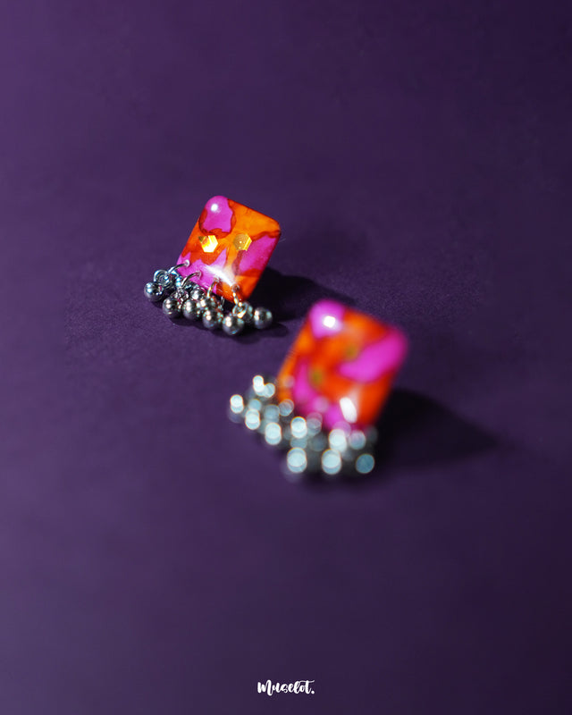 The Laalsavera stud earrings exude elegance with their simple yet striking design, set against a rich purple background — Muselot.