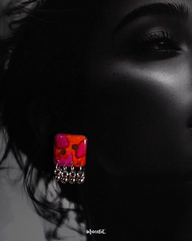 A close-up shot of a model wearing the Laalsavera stud earrings with effortless grace, the bold background enhancing the earrings refined silhouette and artistic flair – Muselot