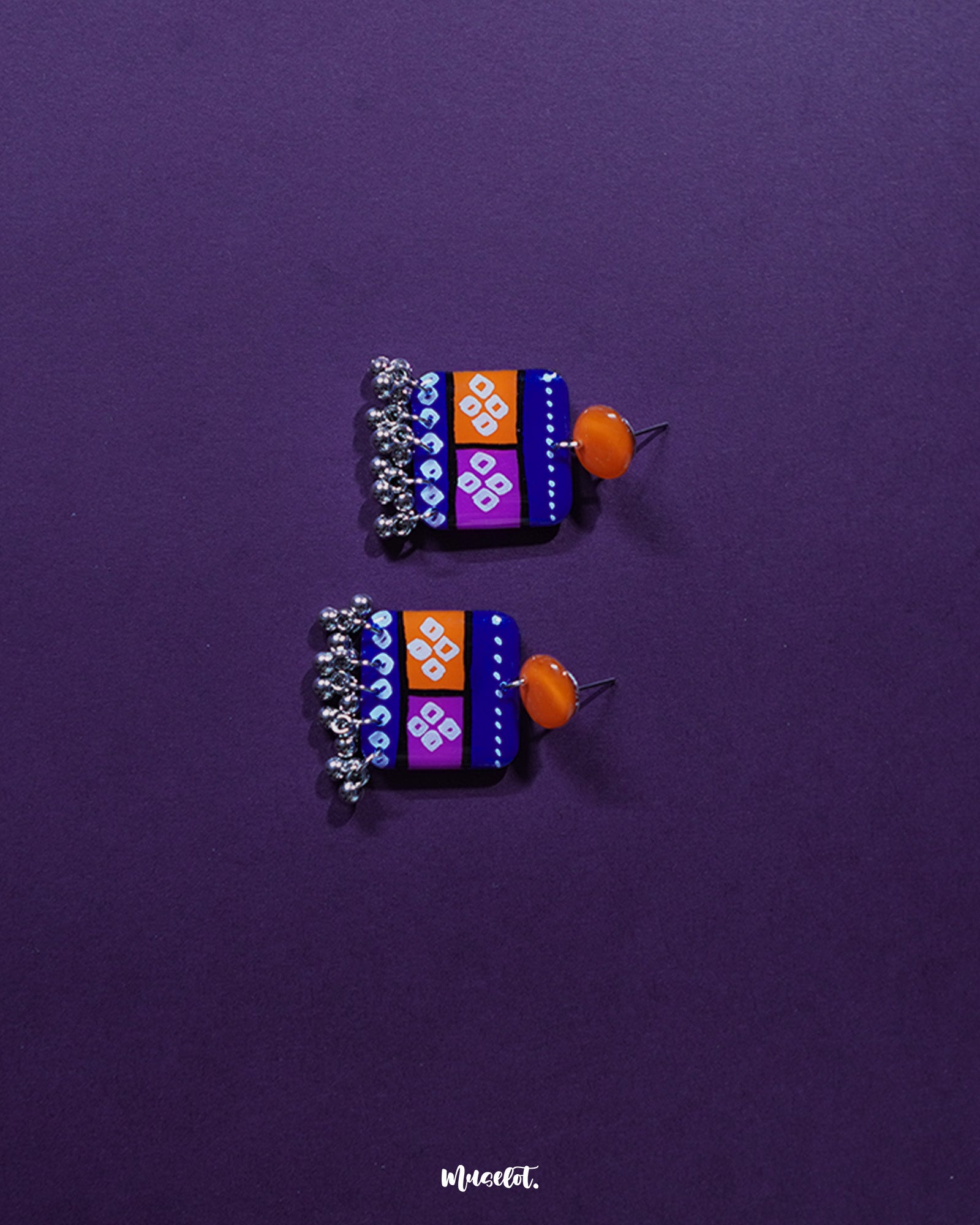 Leheriya traditional art drop earrings featuring bright orange round studs connected to blue rectangular drops with orange and magenta blocks, decorated with white geometric patterns and dotted detailing, finished with dangling silver beads, beautifully showcased to highlight their vibrant, handcrafted design – Muselot.