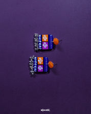 Leheriya traditional art drop earrings featuring bright orange round studs connected to blue rectangular drops with orange and magenta blocks, decorated with white geometric patterns and dotted detailing, finished with dangling silver beads, beautifully showcased to highlight their vibrant, handcrafted design – Muselot.