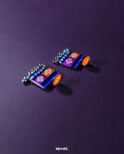 Leheriya traditional art drop earrings featuring vivid orange round studs connected to blue rectangular drops with orange and magenta blocks, embellished with white geometric patterns and dotted accents, finished with dangling silver beads, elegantly presented to highlight their colorful and artistic craftsmanship – Muselot.