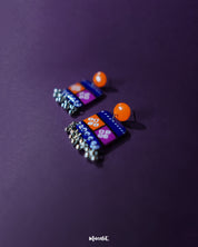 Leheriya traditional art drop earrings with bright orange round studs attached to blue rectangular drops featuring orange and magenta blocks, adorned with intricate white geometric patterns and dotted detailing, finished with dangling silver beads, showcased to emphasize their vibrant handcrafted design – Muselot.