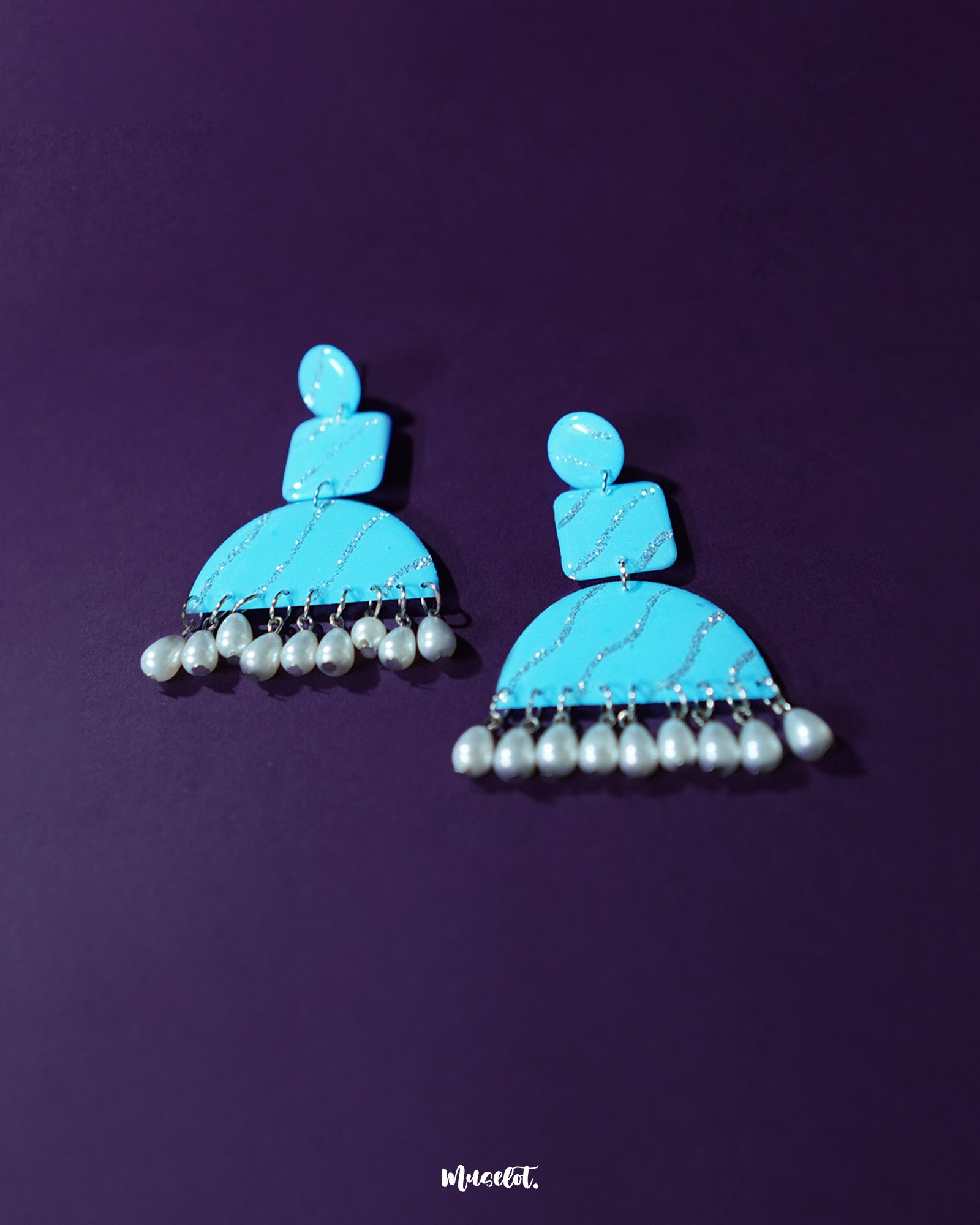 A captivating pair of Lehrbaan blue pearl jhumkas, featuring intricate gold-toned detailing and soft pearl drops that sway beneath rich blue domes, adding a timeless elegance to any festive or traditional ensemble — Muselot.
