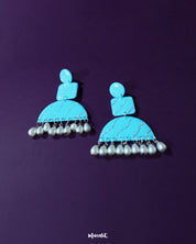 A captivating pair of Lehrbaan blue pearl jhumkas, featuring intricate gold-toned detailing and soft pearl drops that sway beneath rich blue domes, adding a timeless elegance to any festive or traditional ensemble — Muselot.