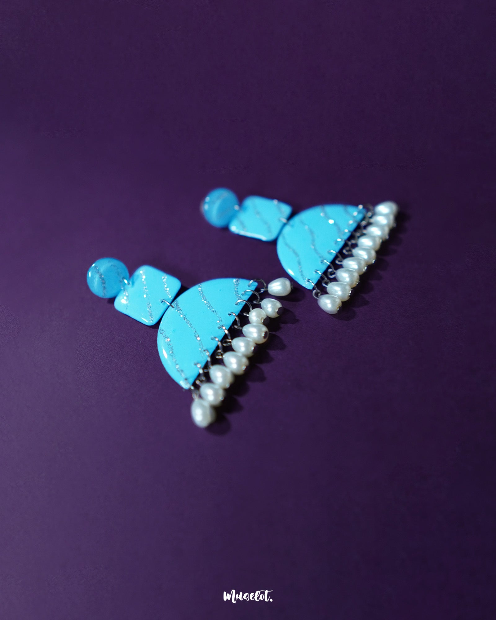 A graceful shot of the Lehrbaan blue pearl jhumkas resting elegantly, showcasing their detailed filigree dome and cascading pearl tassels — Muselot.