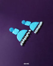 A graceful shot of the Lehrbaan blue pearl jhumkas resting elegantly, showcasing their detailed filigree dome and cascading pearl tassels — Muselot.