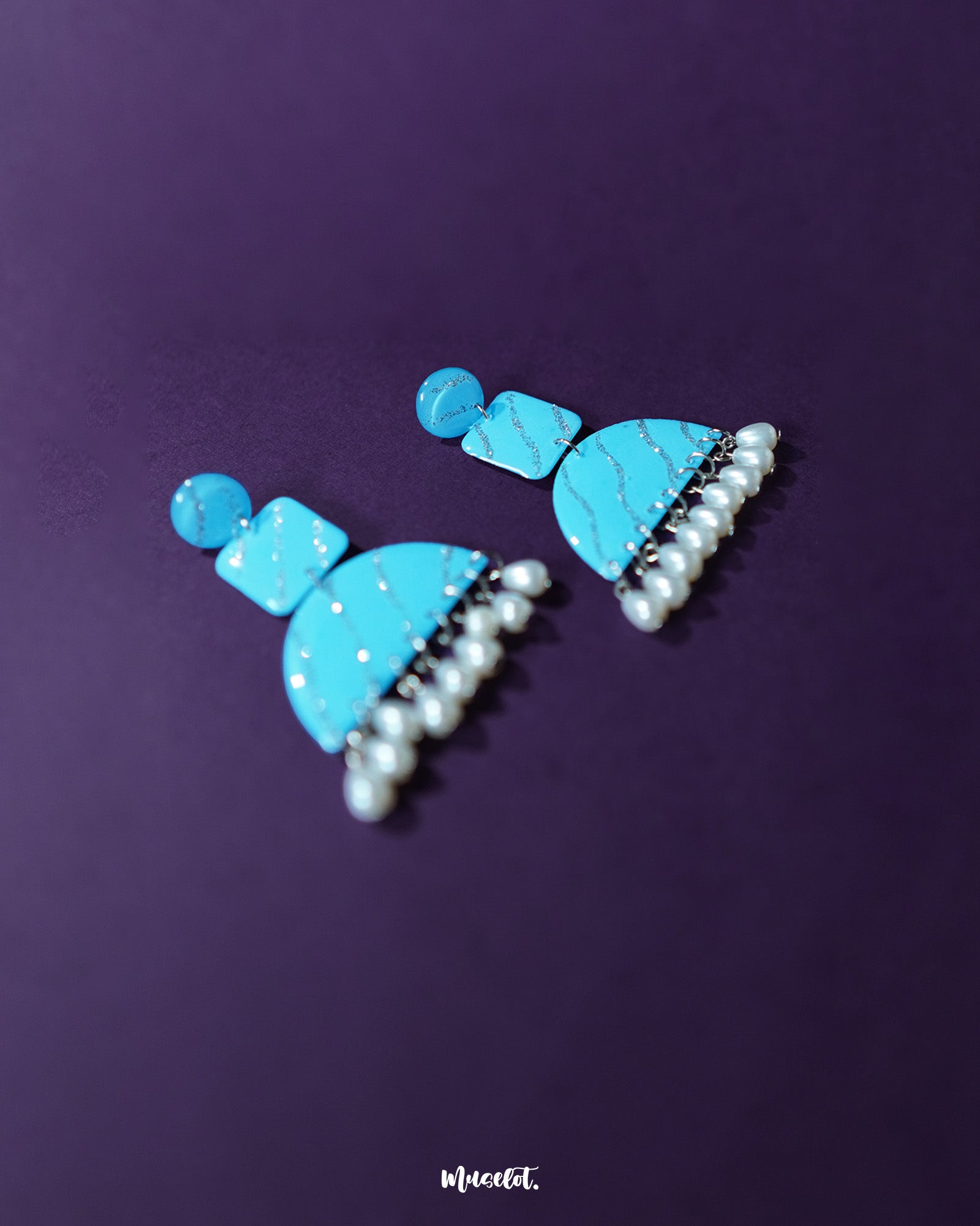 A striking image of the Lehrbaan blue pearl jhumkas displayed on a fabric surface, highlighting the deep navy enamel and the subtle gleam of clustered pearl droplets — Muselot.
