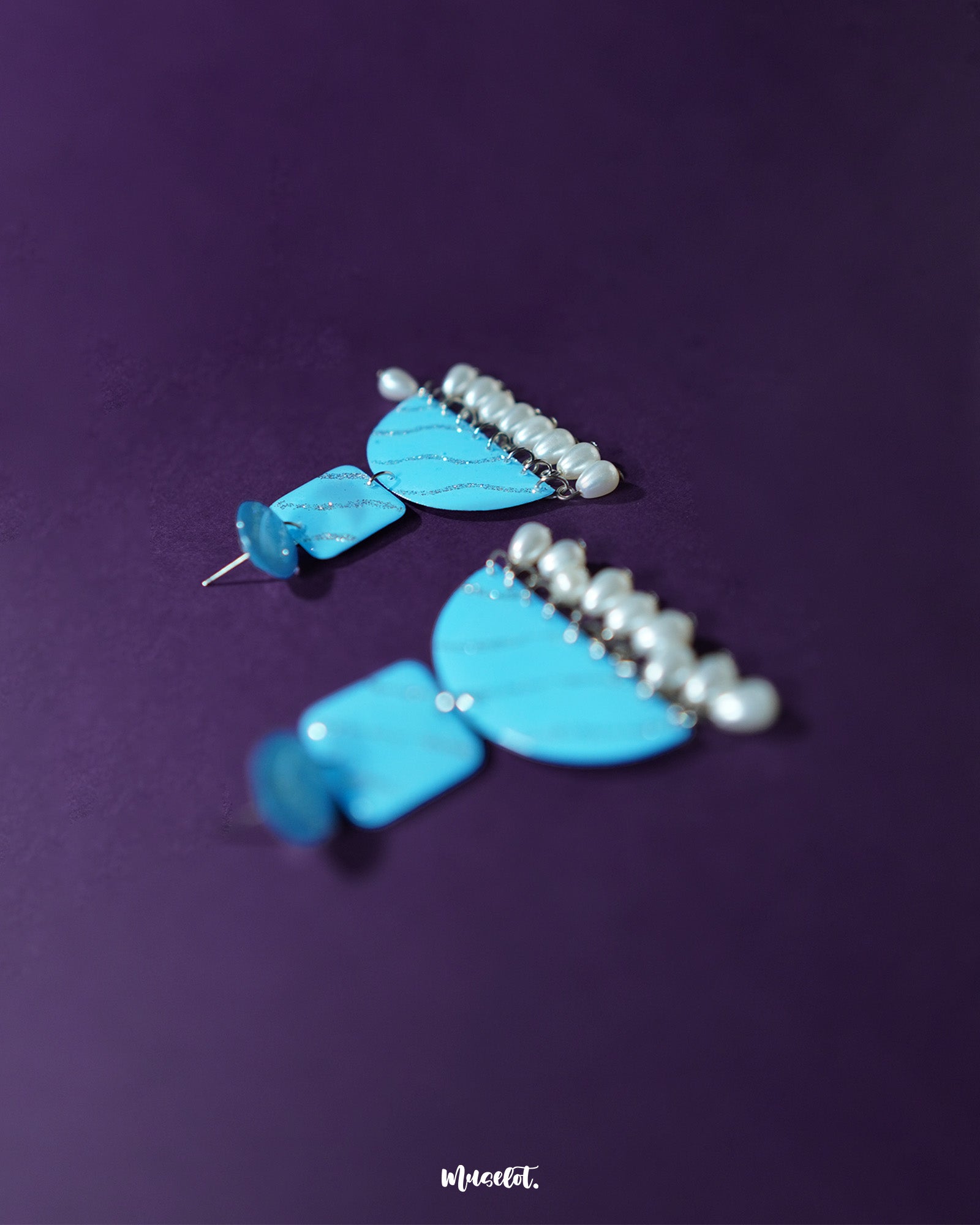 Lehrbaan blue pearl jhumkas laid flat on soft fabric, capturing their glistening navy blue enamel dome and delicate pearl accents in a graceful, symmetrical composition — Muselot.